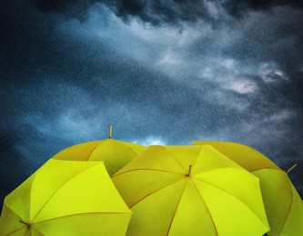 Image of Yellow umbrellas under heavy rain. Stormy weather