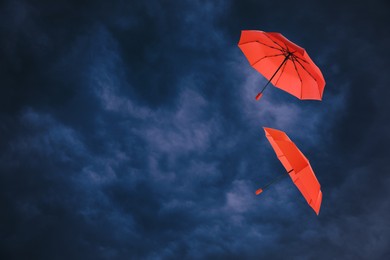 Image of Red umbrellas flying in dark cloudy sky. Stormy weather