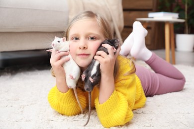 Photo of Little girl with cute rats on floor at home