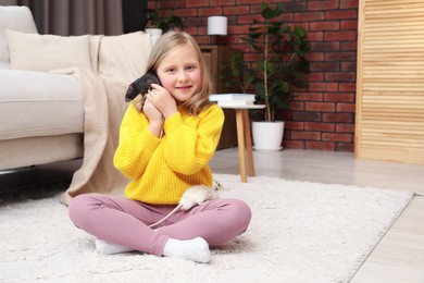 Photo of Little girl with cute rats on floor at home, space for text