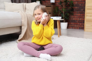 Photo of Little girl with cute white rat on floor at home