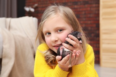 Photo of Little girl with cute black rat at home