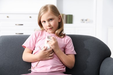 Photo of Little girl with cute white rat on sofa at home