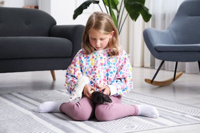 Photo of Little girl with cute rats on floor at home
