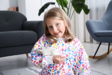 Photo of Little girl with cute white rat at home