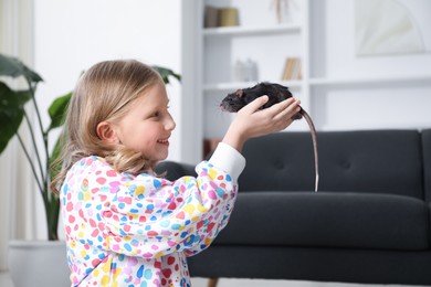 Photo of Little girl with cute black rat at home