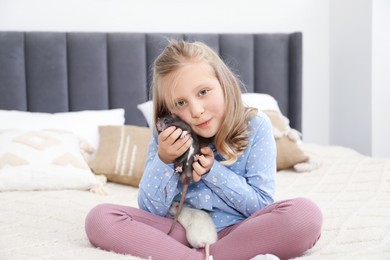 Photo of Little girl with cute rats on bed at home