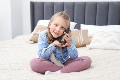 Photo of Little girl with cute rats on bed at home