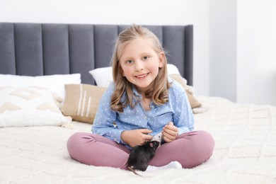 Photo of Little girl with cute rats on bed at home