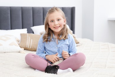 Photo of Little girl with cute rats on bed at home