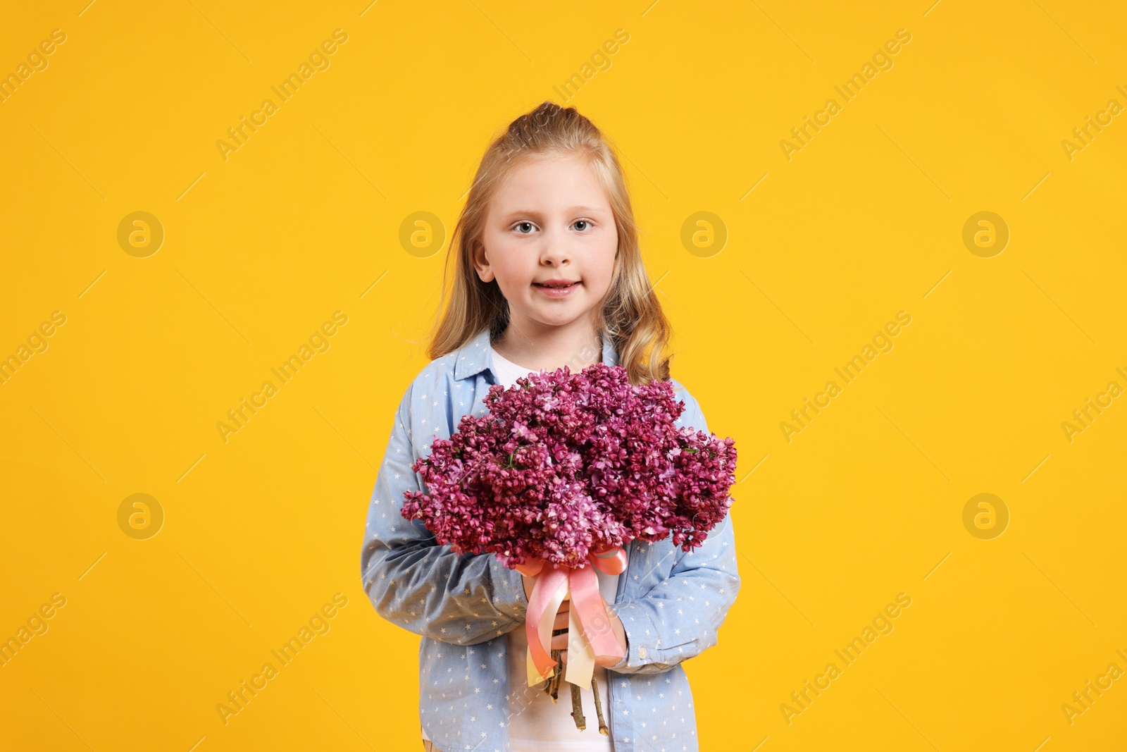 Little girl with bouquet of lilac flowers on yellow background Photo of Little girl with bouquet of lilac flowers on yellow background