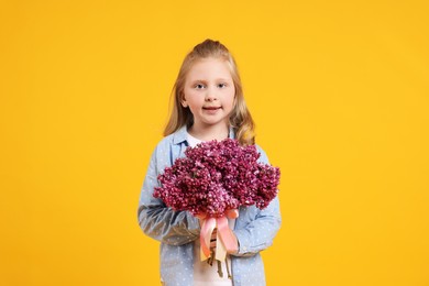 Photo of Little girl with bouquet of lilac flowers on yellow background