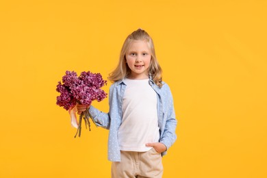 Photo of Little girl with bouquet of lilac flowers on yellow background