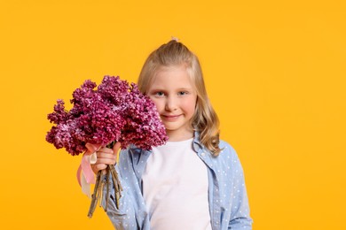 Photo of Little girl with bouquet of lilac flowers on yellow background