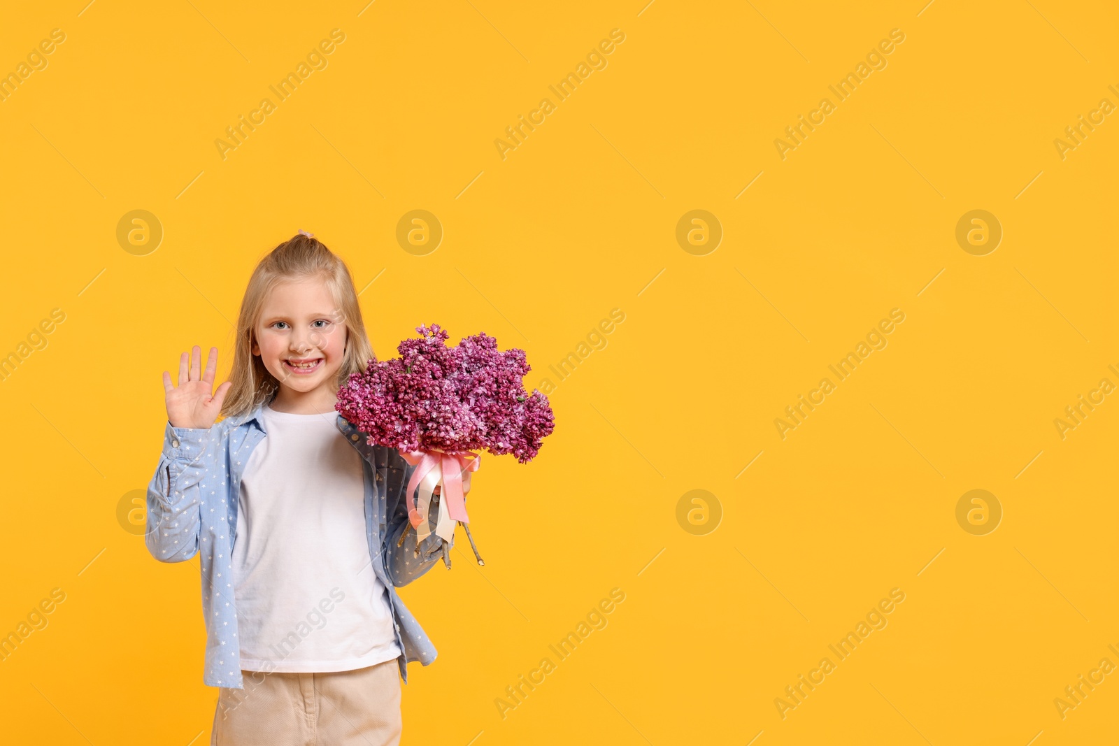 Little girl with bouquet of lilac flowers on yellow background, space for text Photo of Little girl with bouquet of lilac flowers on yellow background, space for text