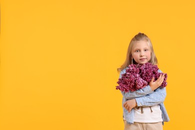 Photo of Little girl with bouquet of lilac flowers on yellow background, space for text