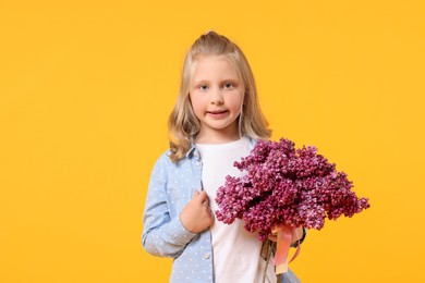 Photo of Little girl with bouquet of lilac flowers on yellow background
