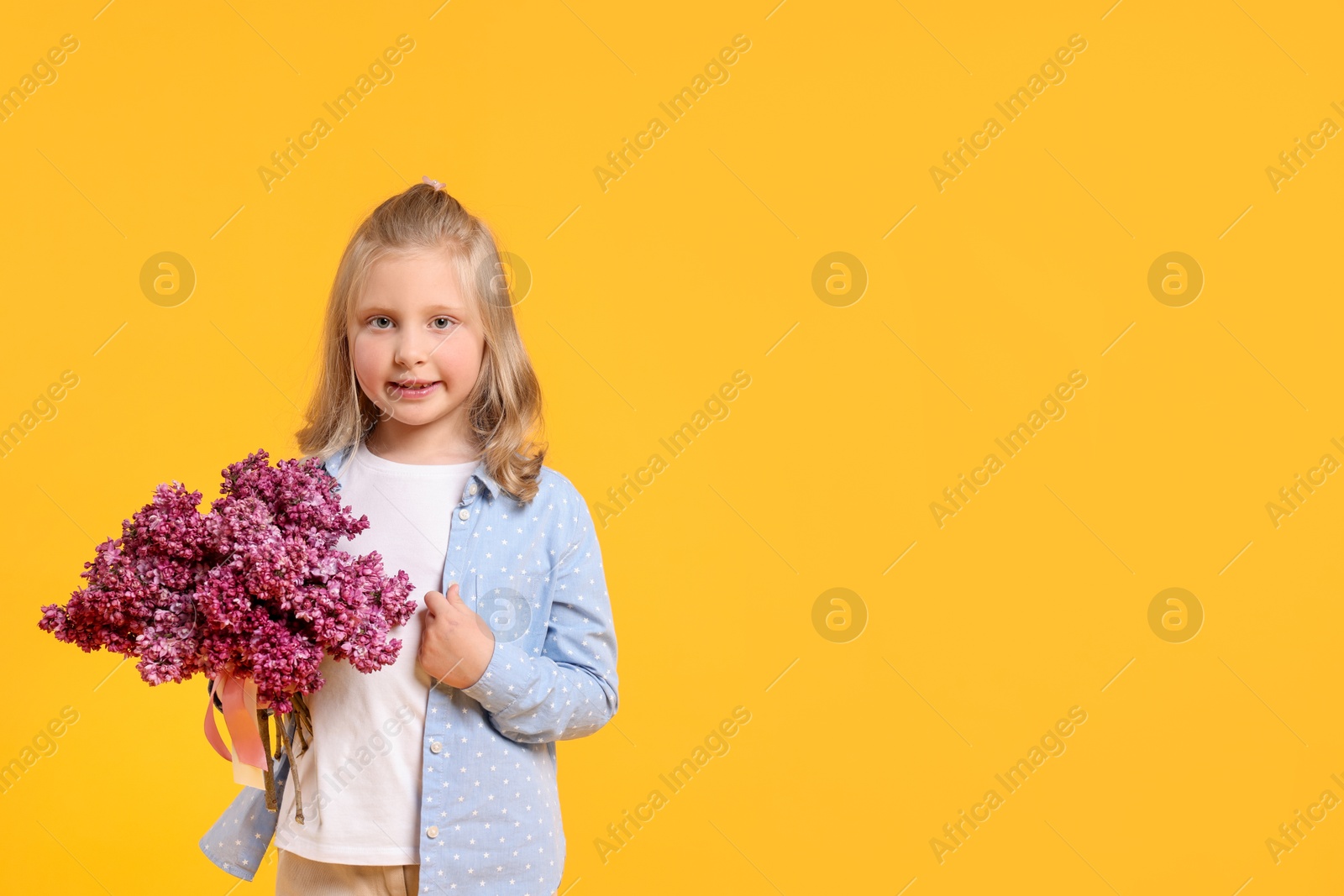 Little girl with bouquet of lilac flowers on yellow background, space for text Photo of Little girl with bouquet of lilac flowers on yellow background, space for text