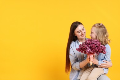 Photo of Mother and her daughter with bouquet of lilac flowers on yellow background, space for text
