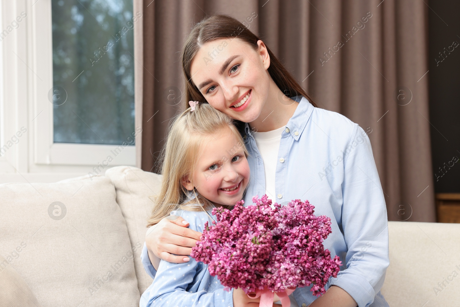 Mother and her daughter with bouquet of lilac flowers at home Photo of Mother and her daughter with bouquet of lilac flowers at home