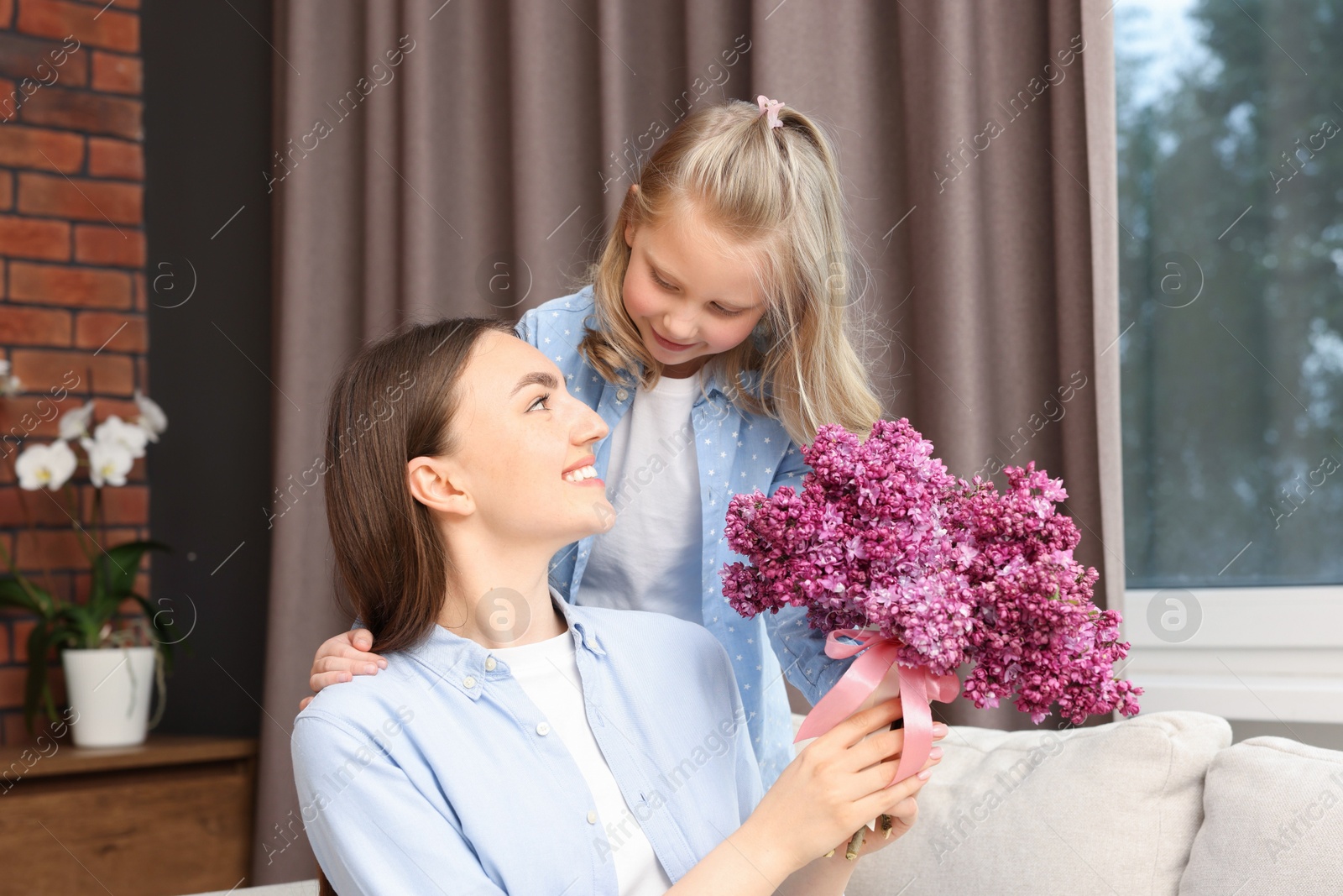 Mother and her daughter with bouquet of lilac flowers at home Photo of Mother and her daughter with bouquet of lilac flowers at home