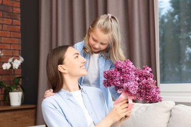 Photo of Mother and her daughter with bouquet of lilac flowers at home