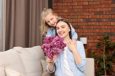 Photo of Mother and her daughter with bouquet of lilac flowers at home