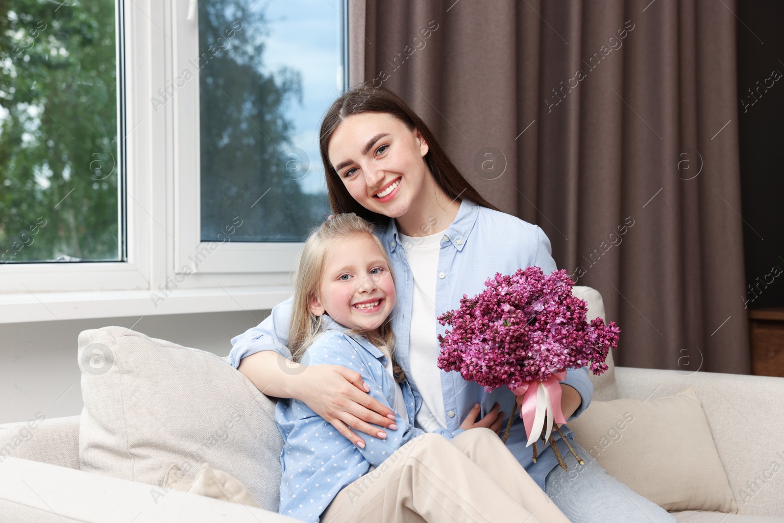 Mother and her daughter with bouquet of lilac flowers at home Photo of Mother and her daughter with bouquet of lilac flowers at home