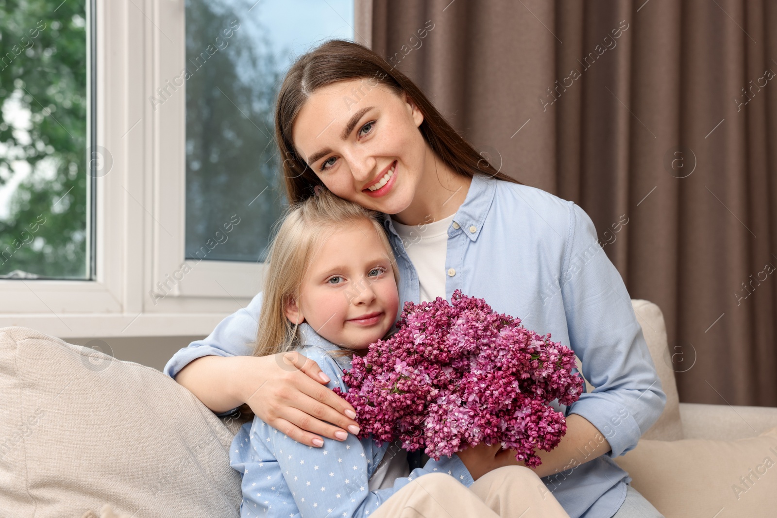 Mother and her daughter with bouquet of lilac flowers at home Photo of Mother and her daughter with bouquet of lilac flowers at home