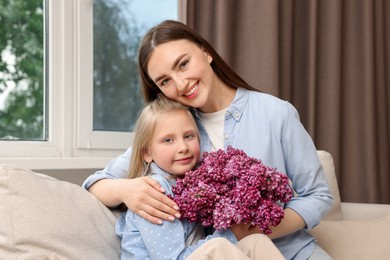 Photo of Mother and her daughter with bouquet of lilac flowers at home