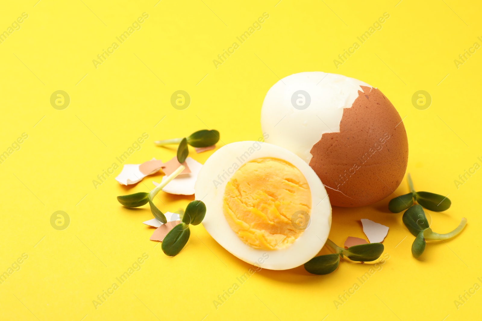 Hard boiled eggs with microgreens on yellow background, closeup. Space for text Photo of Hard boiled eggs with microgreens on yellow background, closeup. Space for text