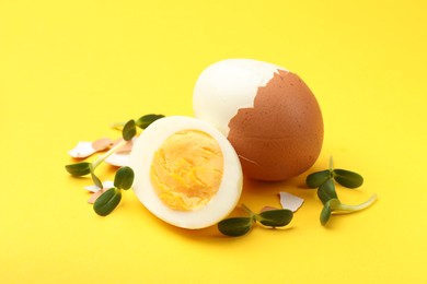 Photo of Hard boiled eggs with microgreens on yellow background, closeup