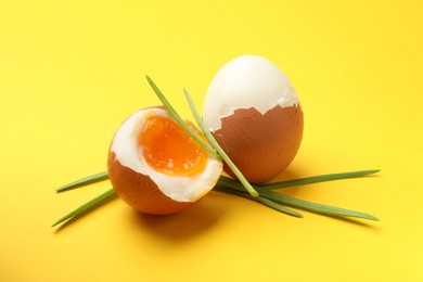 Photo of Soft boiled eggs with green onions on yellow background, closeup