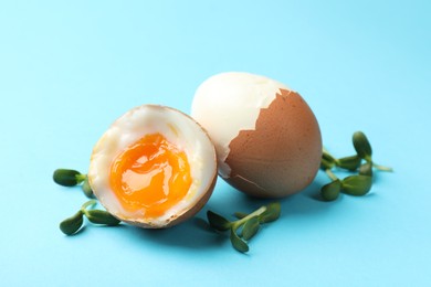 Photo of Soft boiled eggs with microgreens on light blue background, closeup