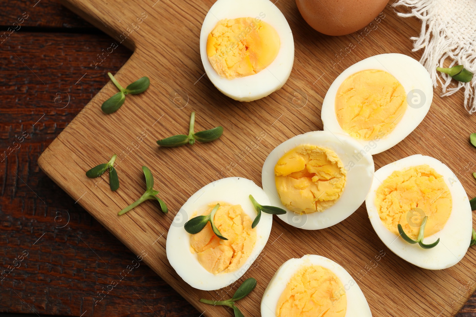 Halves of hard boiled eggs with microgreens on wooden table, top view Photo of Halves of hard boiled eggs with microgreens on wooden table, top view