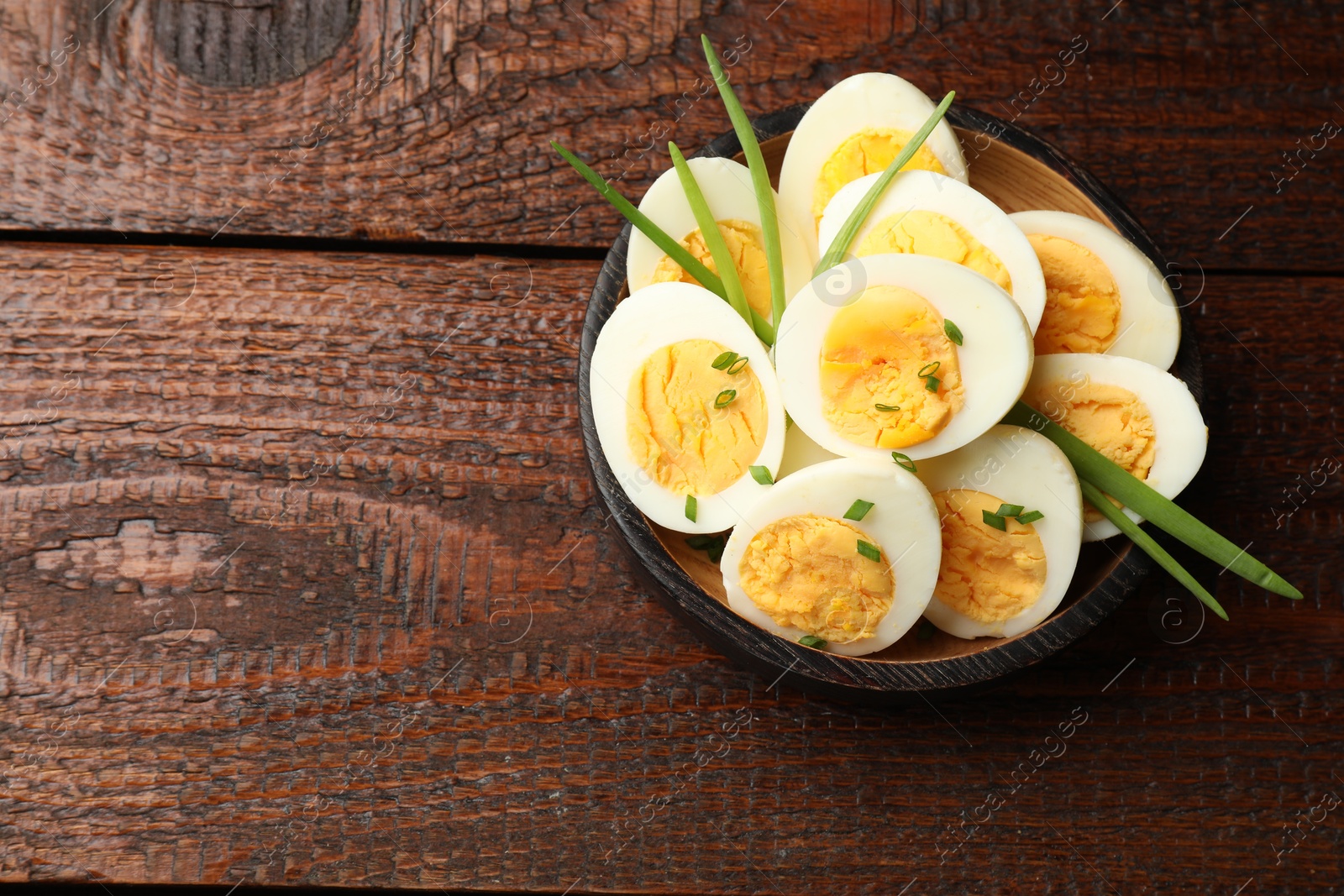 Halves of hard boiled eggs with green onions on wooden table, top view. Space for text Photo of Halves of hard boiled eggs with green onions on wooden table, top view. Space for text