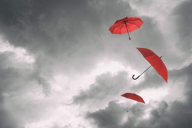 Image of Red umbrellas flying in cloudy sky. Stormy weather