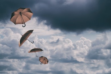 Image of Brown umbrellas flying in cloudy sky. Stormy weather