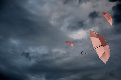 Image of Umbrellas flying in dark cloudy sky. Stormy weather