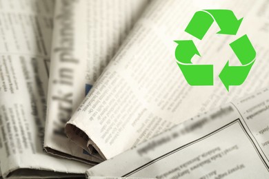 Image of Recycling symbol and many newspapers as background, closeup. Eco-friendly lifestyle, reusing