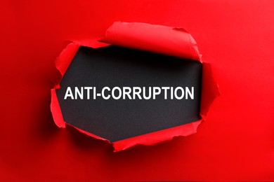 Image of Word Anti-Corruption on black background, view through hole in red paper
