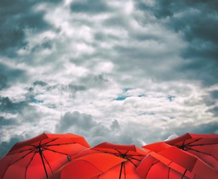 Image of Red umbrellas under cloudy sky. Stormy weather