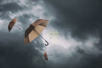 Image of Brown umbrellas flying in dark cloudy sky. Stormy weather