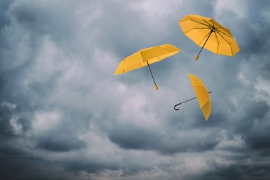 Image of Orange umbrellas flying in cloudy sky. Stormy weather