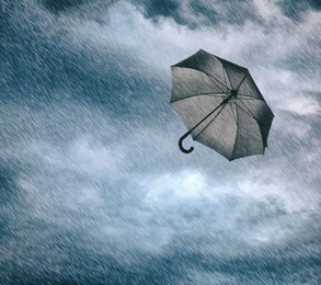 Image of Black umbrella flying in cloudy sky under heavy rain. Stormy weather