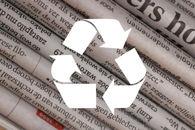 Image of Recycling symbol and many newspapers in different languages as background, closeup. Eco-friendly lifestyle, reusing