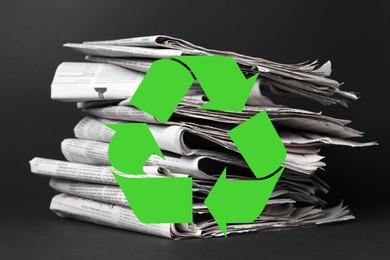 Image of Recycling symbol and many newspapers on grey table. Eco-friendly lifestyle, reusing