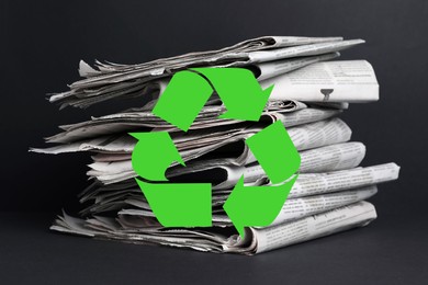 Image of Recycling symbol and many newspapers on grey table. Eco-friendly lifestyle, reusing