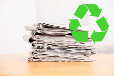Image of Recycling symbol and stack of many newspapers on wooden table, closeup. Eco-friendly lifestyle, reusing