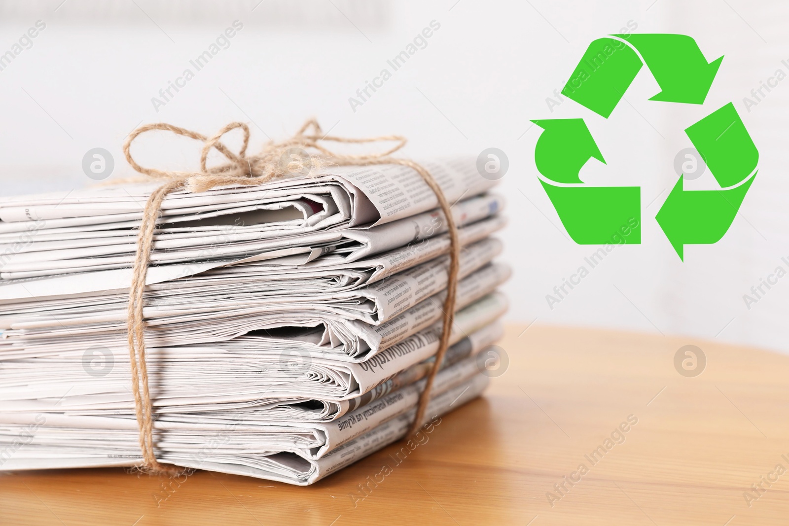 Recycling symbol and stack of tied newspapers on wooden table, closeup. Eco-friendly lifestyle, reusing Image of Recycling symbol and stack of tied newspapers on wooden table, closeup. Eco-friendly lifestyle, reusing
